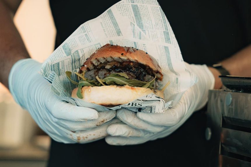 Frisch zubereiteter Burger im Papier wird über die Theke gereicht